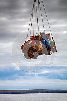 Helicopter carries sling rope mesh with empty metal barrels