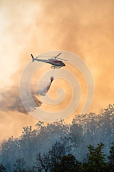 Helicopter dumping water on forest fire