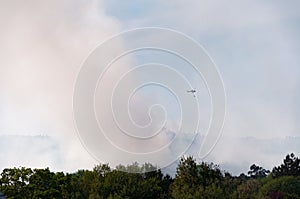 Helicopter firefighter flying over smoke column in forest fire
