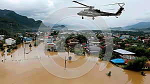 A helicopter flies over a flooded town delivering food and medical supplies to the stranded residents