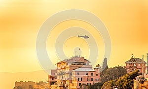 Helicopter flies over the houses during a fire at sunset