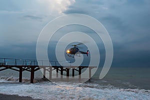 Helicopter, flies up during a marine gale. Air transport in bad weather conditions