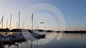 Helicopter fly while dusk over sailing boats