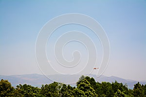Helicopter fly over mountain and tree in a clear sky