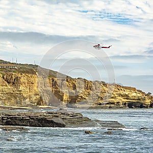 Helicopter flying on cloudy sky over Sunset Cliffs