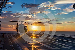 helicopter landing on the deck of a supply vessel at sunset