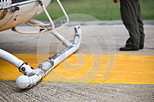 Helicopter landing skids on helipad and pilot backgroun