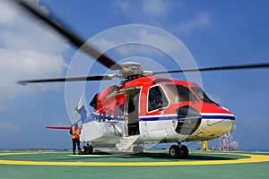 The helicopter is landing to embark passenger at oil rig platform photo
