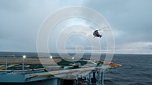 The helicopter lands on the deck with a hover. A training flight with a training landing on the helipad of a moving ship