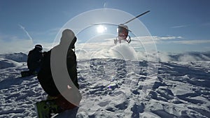 The helicopter left skiers on the slope of the mountain and flew raising a cloud of snow