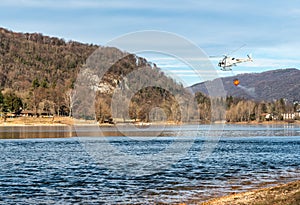 The helicopter load water from Lake Ghirla to extinguish the mountain flames in Valganna, Italy. photo