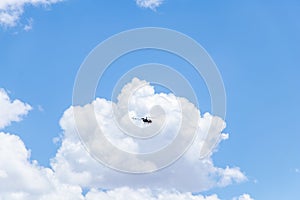 A helicopter mid-air for air surveillance and rescue with a huge cloud formation behind
