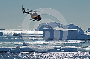 Helicopter over Antarctic icebergs photo