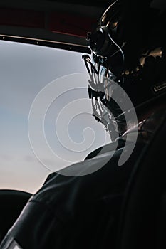 Helicopter pilot and helmet with blue sky ahead in the cabin, vertical shot