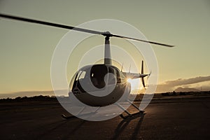 Helicopter on the runway at sunset.