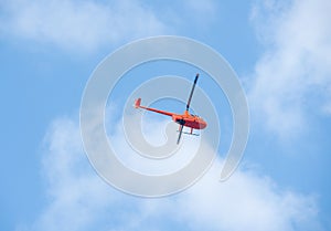 Helicopter in the sky on blue sky red orange helicopter flying in summer