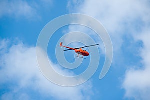 Helicopter in the sky on blue sky red orange helicopter flying in summer