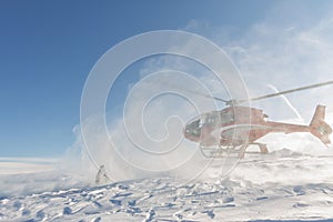 Heliski helicopter takes off in snow powder freeride landed on mountain photo