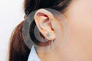 Helix cartilage piercing for girl and earlobe close up. photo