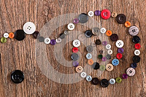 Helix of colorful sewing buttons on a wooden background