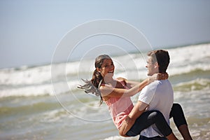 Hell catch me when I fall. a young couple being playful on the beach.