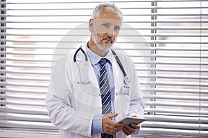 Hell get you better in no time. Portrait of a mature male doctor holding a digital tablet.