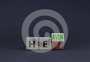 Hell or heaven symbol. Turned a wooden cube and changed the concept word Hell to Heaven. Beautiful grey table, grey background,