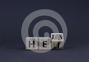 Hell or heaven symbol. Turned a wooden cube and changed the concept word Hell to Heaven. Beautiful grey table, grey background,