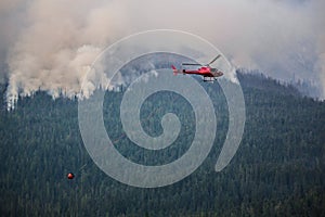 Hellicopter slinging water bucket to fire.