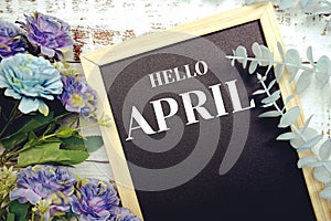 Hello April typography text and flower decoration on blackboard background