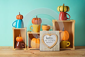 Hello Autumn concept with heart shape photo frame and pumpkin decor on wooden table over blue background