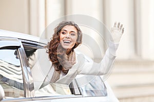 Hello! Beautiful young woman looking out from a car saying hello