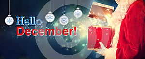 Hello December message with Santa opening a gift box