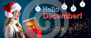 Hello December message with woman opening a gift box