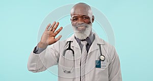 Hello, doctor and face of senior man in studio waving, greeting or attention gesture on blue background. Hand, wave and