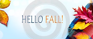 Hello fall message with Autumn leaves and Warm scarf on a blue background