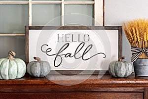 Hello fall sign and neutral colored pumpkins on wood mantel