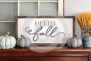 Hello fall sign and neutral colored pumpkins on wood mantel photo