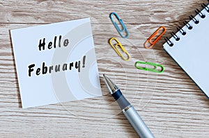 Hello February on peace of paper near office suplies at workplace background