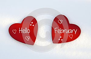 Hello February.Two red wooden hearts on natural white snow background.Winter holidays or Valentines Day concept.