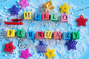 Hello February written on colour wooden toy cubes On light background with snow