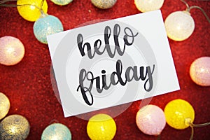 Hello Friday text on paper card top view on red bokeh background