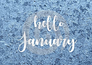 Hello January.Frosty natural pattern on winter window.Ice embroidered lace on the glass with text.
