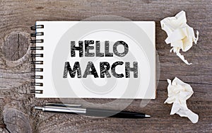 Hello March. On a wooden table notebook and pen