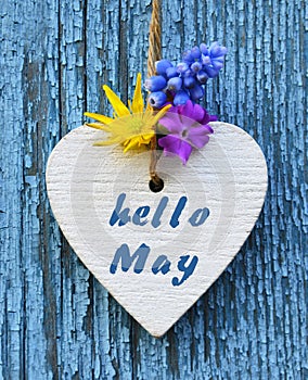 Hello May greeting card with decorative white heart and spring flowers on old blue wooden background.