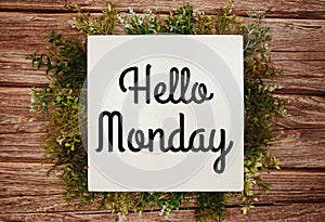 Hello Monday text message with green leaves decoration on wooden background