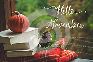 Hello November. Cozy autumn still life: cup and opened book on vintage windowsill with red blanket, pumpkin, candles. Autumn. Rain