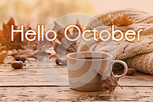 Hello October card. Cup of hot drink and autumn leaves on table