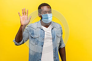 Hello! Portrait of positive handsome man with medical mask with rolled up sleeves smiling friendly and waving hand saying hi,