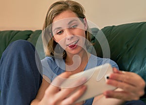 Hello social media, hello world. a young woman pulling a funny face while taking a selfie with her smatphone at home.